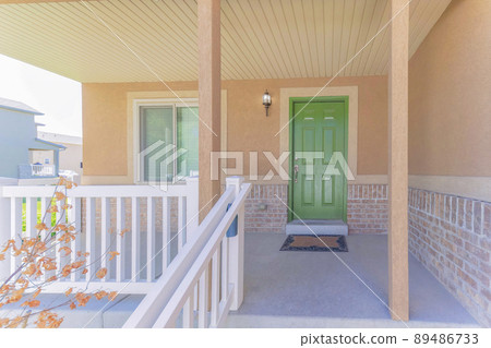 Porch of a house with white railings with lockbox and green front door Porch of a house with white railings with lockbox and green front door 89486733