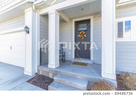 House porch with rocking chair near the black front door with glass panel and wreath House porch with rocking chair near the black front door with glass panel and wreath 89486736