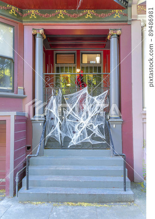 Facade of a house with fake holloween spider webs at the front gate in San Francisco, California 89486981
