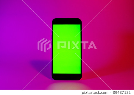 Mobile phone with green screen, smartphone mock up. Neon illumination. Pink and purple color. Flat screen modern smartphone Mobile phone with green screen, smartphone mock up. Neon illumination. Pink and purple color. Flat screen modern smartphone 89487121