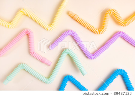 Trendy kids toys pastel colorful pop-tube in baby toddler hands on beige background. Set of forms and colors corrugated pipe and anti stressing, relaxation fidget finger toys. Trendy kids toys pastel colorful pop-tube in baby toddler hands on beige background. Set of forms and colors corrugated pipe and anti stressing, relaxation fidget finger toys. 89487123