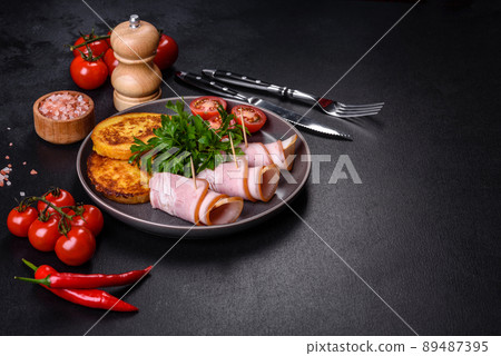 Slices of delicious raw or salted bacon with spices, salt, vegetables and herbs on a wooden cutting board 89487395