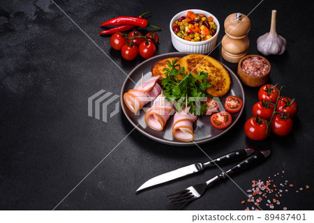 Slices of delicious raw or salted bacon with spices, salt, vegetables and herbs on a wooden cutting board Slices of delicious raw or salted bacon with spices, salt, vegetables and herbs on a wooden cutting board 89487401