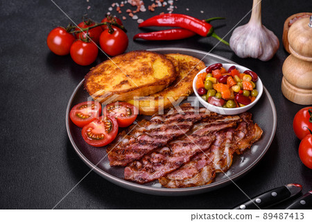 Slices of delicious grilled bacon with croutons fried in egg with spices, salt, vegetables and herbs 89487413