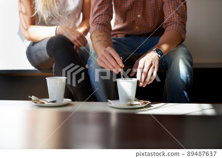 They love their coffee. Cropped image of a young couple enjoying coffee at their local cafe. They love their coffee. Cropped image of a young couple enjoying coffee at their local cafe. 89487637