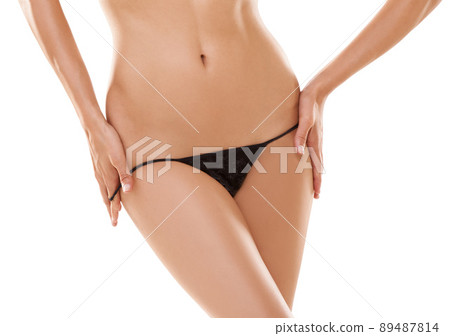 Tempting curves. Cropped view of a sexy womans waist and thighs as she slips off a thong. 89487814