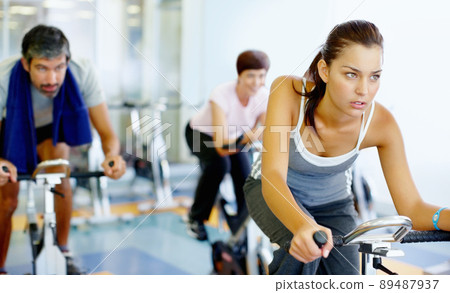Woman practicing on speed bike at gym. Beautiful woman working out on a stationary bike at the gym. Woman practicing on speed bike at gym. Beautiful woman working out on a stationary bike at the gym. 89487937