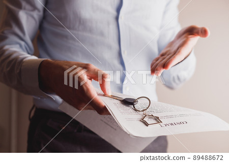 Manager offers keys to house holding contract in other hand. Manager offers keys to house holding contract in other hand. 89488672