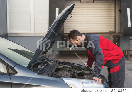 Auto mechanic examines car under the hood during technical inspection of car 89488724