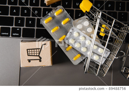 Trolley with medicines and card boxes on a laptop. Close-up. Concept for online trade and sales of medicines and vitamins Trolley with medicines and card boxes on a laptop. Close-up. Concept for online trade and sales of medicines and vitamins 89488756
