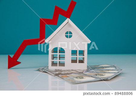 Wooden house and a red arrow down with money banknotes. The concept of inflation and economic recession 89488806