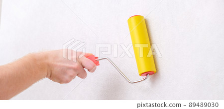 A man rolls out a canvas of white wallpaper with a A man rolls out a canvas of white wallpaper with a 89489030