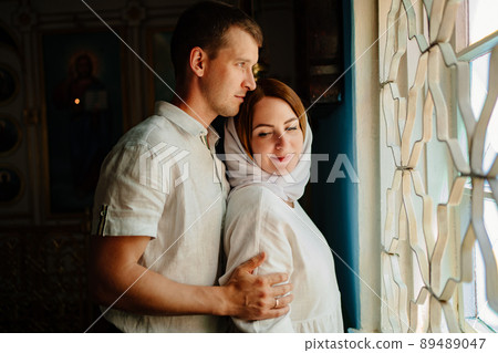 man and woman in headscarf and light-colored robes by window in church. man and woman in headscarf and light-colored robes by window in church. 89489047