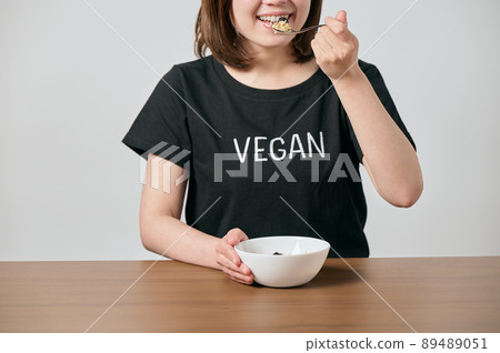 Young vegan woman eating oatmeal 89489051