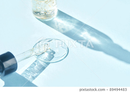 Serum gel texture swatch. Transparent drop with golden sparkles. Blue background 89494483