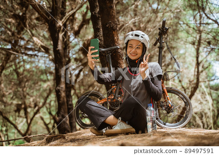 veiled girl smiling wearing earphones while selfie using cellphone 89497591