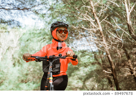 asian woman in sunglasses cycling in park with trees background 89497678