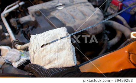 Car service. Mechanic man checks the oil state. The oil needs replacement 89499298