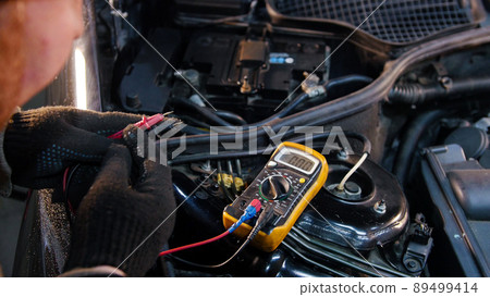 Car service. Mechanic man checks the voltage with a multimeter 89499414