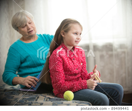 Grandmother brushing long hair to her granddaughter 89499441