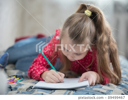 Girl spend time at home drawing while lying on the bed 89499467