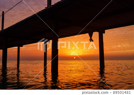 legs of woman who sitting on wooden bridge with beautiful sea landscape at sunrise legs of woman who sitting on wooden bridge with beautiful sea landscape at sunrise 89501481