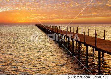 wooden pontoon bridge in sea and picturesque sky with spindrift clouds on sunrise wooden pontoon bridge in sea and picturesque sky with spindrift clouds on sunrise 89501482