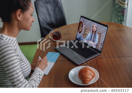 Close up shot of pretty young woman studying having online video lesson sitting in kitchen Close up shot of pretty young woman studying having online video lesson sitting in kitchen 89503517
