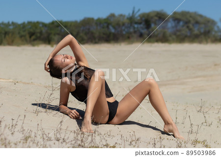 Sensual woman in black underwear relaxing on sandy beach 89503986