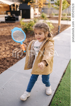 Cute little girl playing badminton in little kids city. Toy city for children Cute little girl playing badminton in little kids city. Toy city for children 89505828