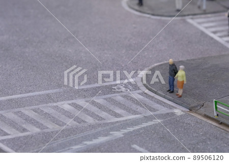 Elderly people trying to cross a pedestrian crossing 89506120
