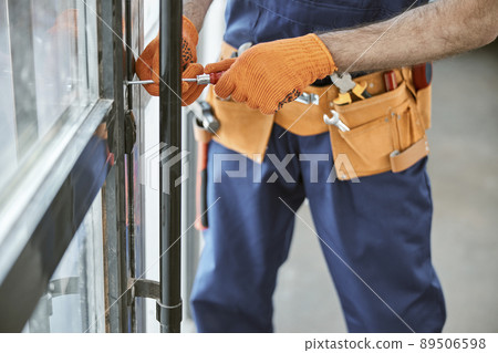 Male worker in work gloves repairing door in house Male worker in work gloves repairing door in house 89506598