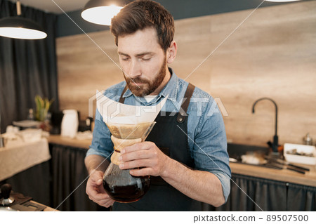 Handsome barista with stylish beard smelling filter coffee in cafeteria 89507500
