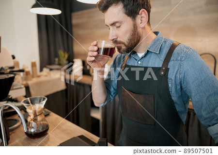Handsome barista with stylish beard smelling filter coffee in cafeteria 89507501
