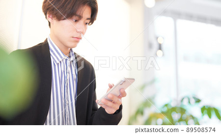 A young man using a smartphone with his left hand A young man using a smartphone with his left hand 89508574