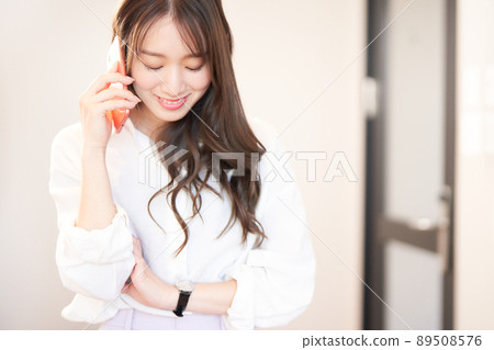 一個微笑的年輕女子在智能手機上交談 89508576