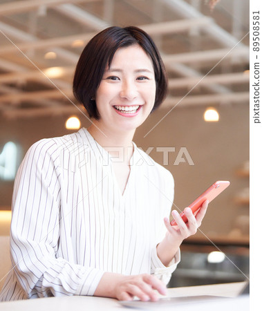 一個微笑的年輕女子在咖啡館裡使用智能手機 89508581