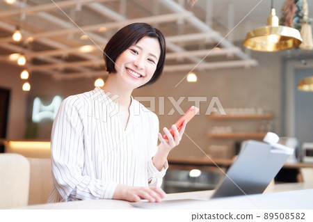 A smiling young woman using a smartphone in a cafe A smiling young woman using a smartphone in a cafe 89508582