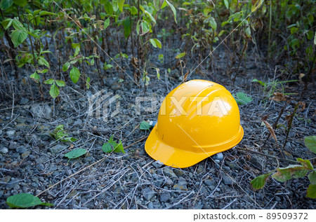 [Japan] An orange helmet placed on a gravel ground with weeds 89509372