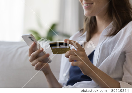 Hands of positive smiling millennial girl paying on Internet stores Hands of positive smiling millennial girl paying on Internet stores 89510224