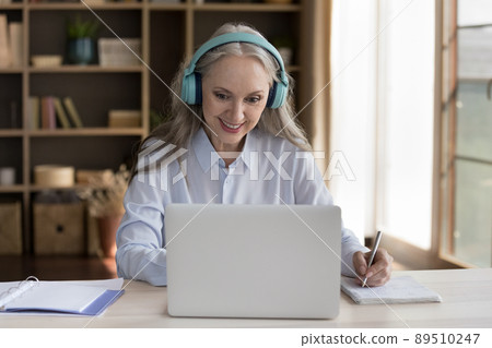 Happy mature training course student woman in wireless earphones Happy mature training course student woman in wireless earphones 89510247