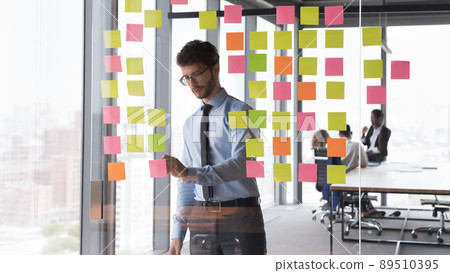 Serious confident young project leader planning tasks for employees 89510395