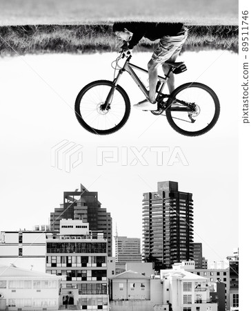 The sky is the limit. A man on a bicycle hovers in the air over the rooftops of a city - perception. 89511746