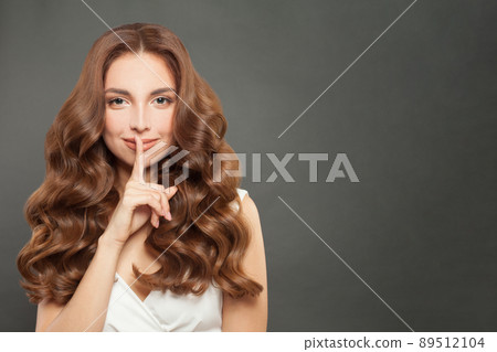 Beautiful woman holding finger near lips, silence and secret concept Beautiful woman holding finger near lips, silence and secret concept 89512104