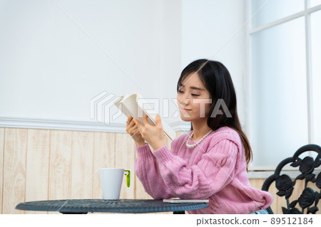 年輕女子在靠窗的座位上看書 89512184