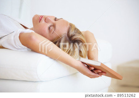 Reading makes her sleepy. An attractive young woman falling asleep on the couch with a book in hand. Reading makes her sleepy. An attractive young woman falling asleep on the couch with a book in hand. 89513262