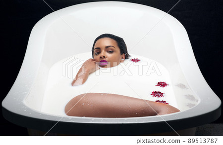 Treating myself and my skin. Portrait of a beautiful young woman submerged in white liquid in a bathtub. 89513787