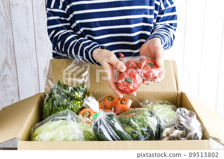 A woman opening a box full of vegetables A woman opening a box full of vegetables 89513802
