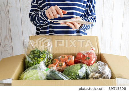 一個女人打開一個裝滿蔬菜的盒子 89513806