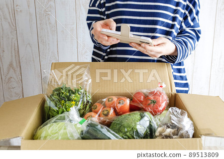 一個女人打開一個裝滿蔬菜的盒子 89513809